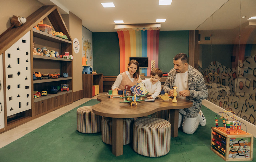 Família brincando no espaço kids do Hotel Fioreze Centro, em Gramado, com brinquedos educativos e ambiente acolhedor.