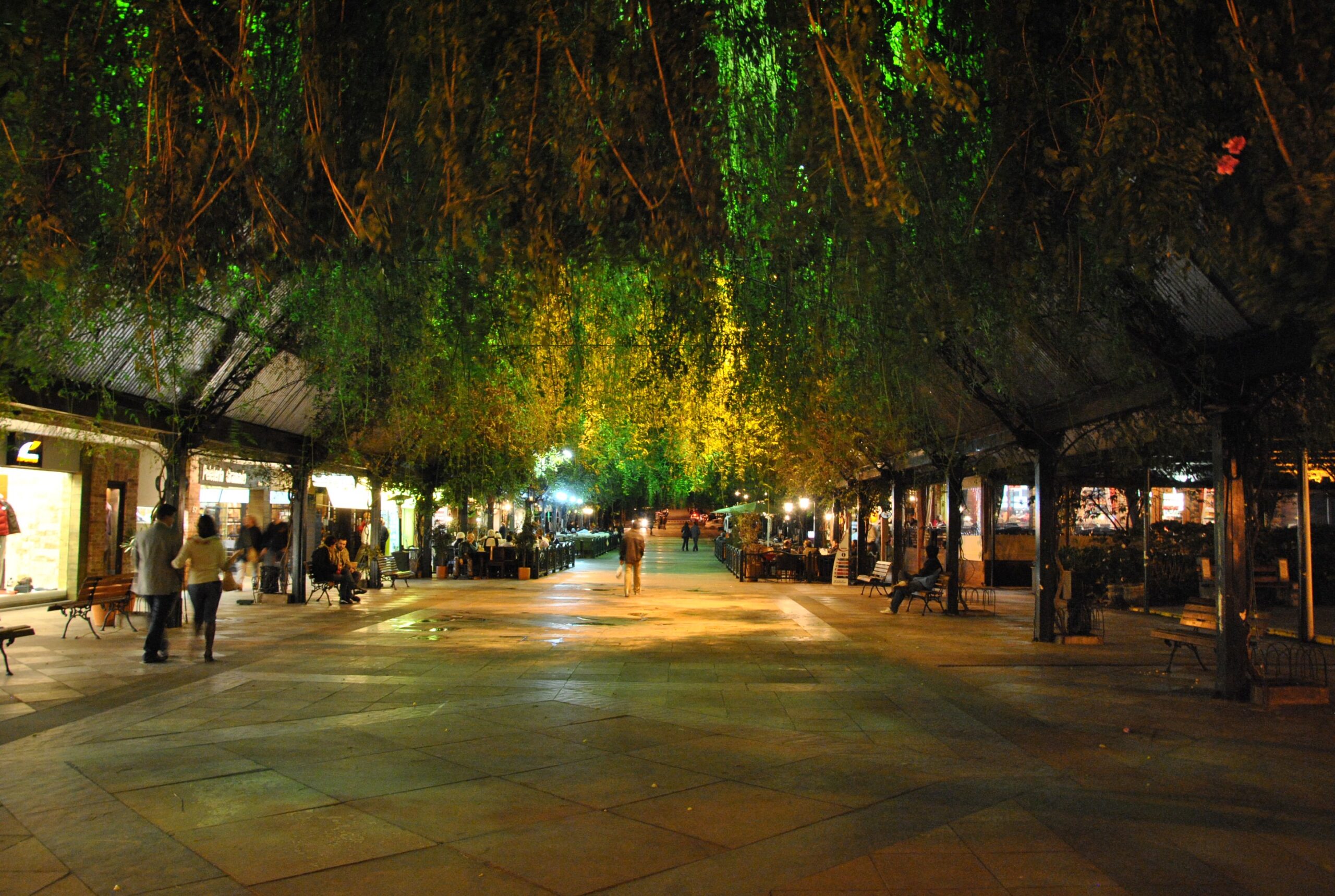 Rua Coberta em Gramado com iluminação, restaurantes e visitantes.